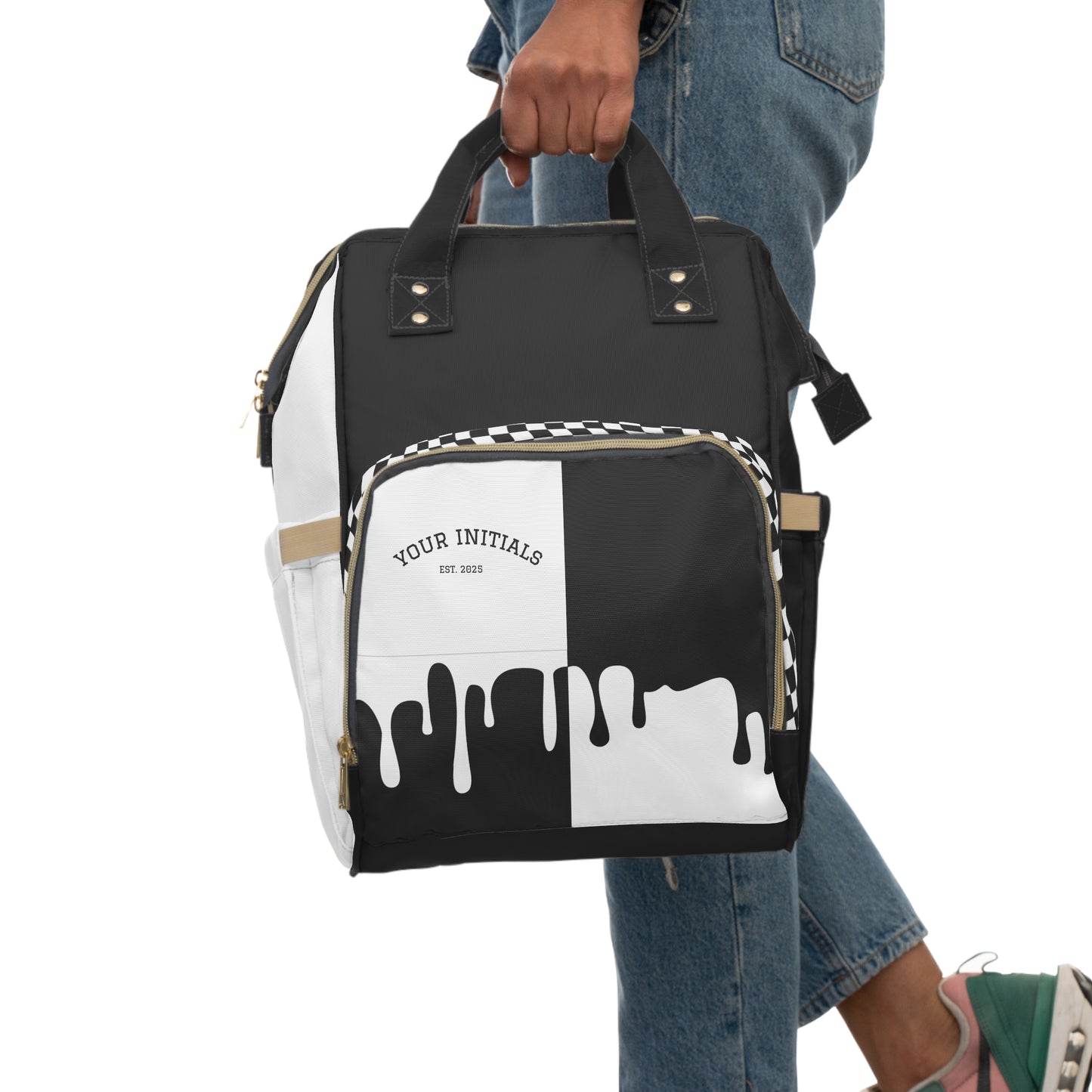 Black and white backpack with a checkered pattern held by a person wearing jeans.