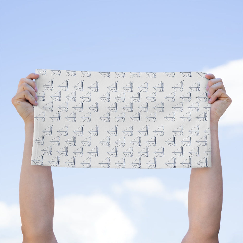 Person holding the PBP Nautical burp cloth with boat pattern against a blue sky