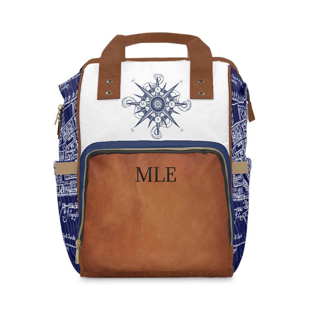 Backpack with blue patterned sides, brown front pocket, and white top section with compass design on a white background.