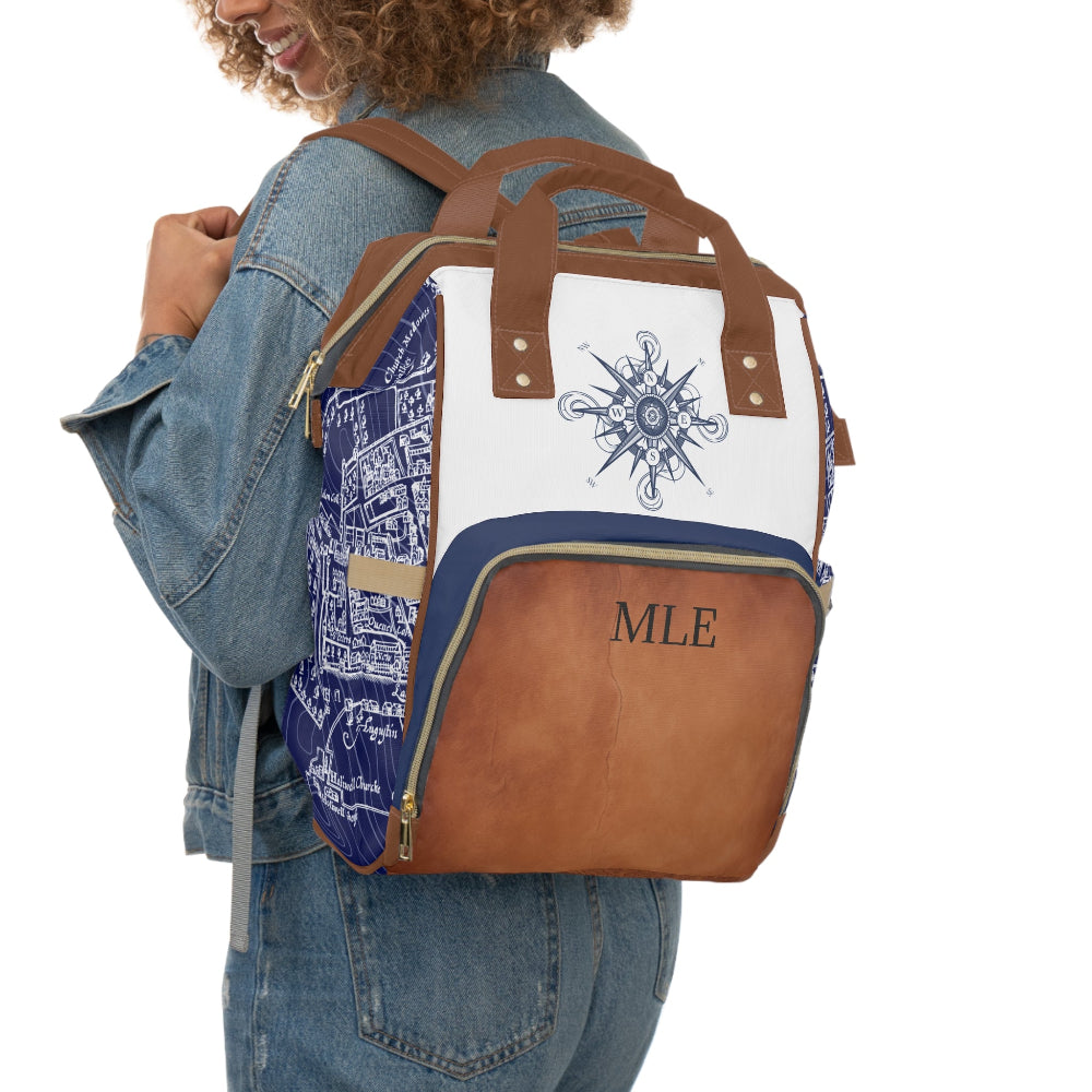 Person wearing a brown and blue backpack with a compass design and 'MLE' initials.