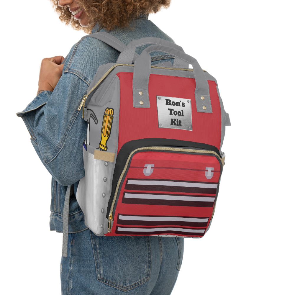 Person wearing a PBP Dad's Tool Box Kit Diaper Backpack with tool box design and 'Ron's Tool Kit' label.